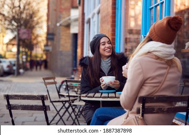 Two Female Friends Meeting Sitting Outside Coffee Shop On City High Street - Powered by Shutterstock