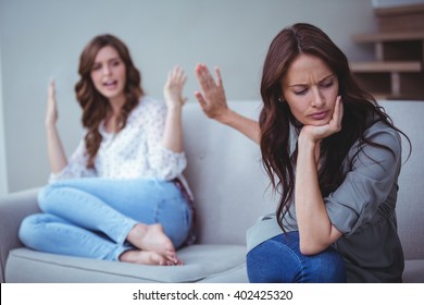 Two Female Friends Sitting On Sofa And Arguing With Each Other