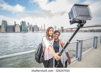 Dos amigas tomando una foto de Nueva York y el puente de Brooklyn - Mejor amigas viajando y grabando su viaje con una cámara de acción