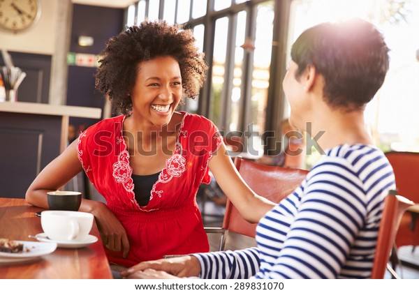 Two female\
friends talking at a coffee\
shop