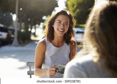 Two Female Friends Talking Over Coffee Outside A Cafe