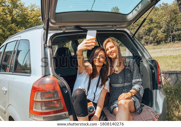 Two female friends travel around the world in a\
car. Vacation concept.