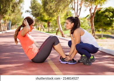 Two Female Friends Working Out Together And Doing Some Crunches Outdoors