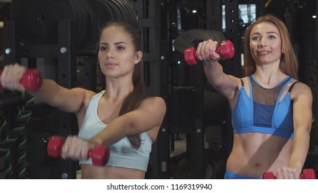 Two Female Frinds Working Out Together At The Gym Lifting Weights