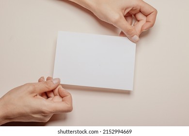 zwei weibliche Hände, die ein leeres Stück Papier mit Kopienraum vor beigem Hintergrund halten