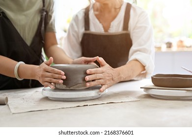 Two female hands making a clay pottery, moulding a clay pottery in the workshop together. Handmade kitchen cookware. cropped shot - Powered by Shutterstock