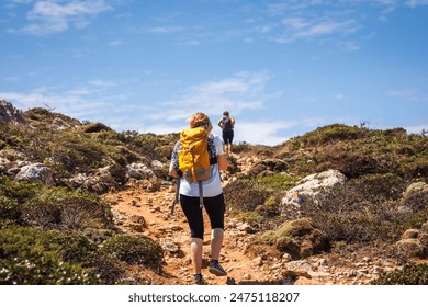 Two female hikers with backpack walking up to cliffs on Algarve coastline in Portugal. Active summer hiking vacation - Powered by Shutterstock