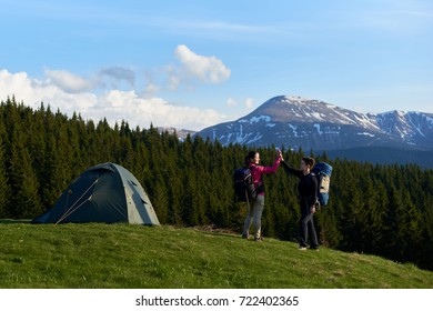 Two Female Hikers High Fiving After Successful Hike In The Mountains Resting On Top Of A Hill Near Their Tent Success Achieving Pride Sportive Active Lifestyle Friendship Partnership.