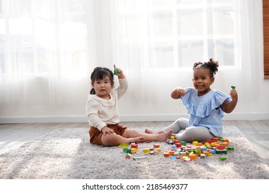 Two female kid playing in the home school with wooden block as creative learning. African girl and Asain girl are playing together with fun. - Powered by Shutterstock