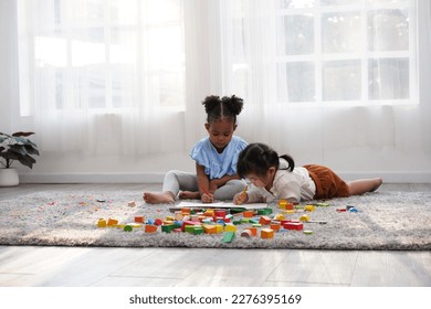 Two female kid playing in the home school with wooden block as creative learning. African girl and Asain girl are playing together with fun. - Powered by Shutterstock