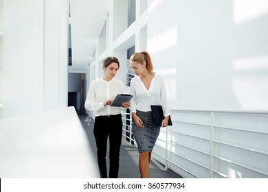 Two female managing directors discussing ideas of project on digital tablet while walking down in office hall, confident women entrepreneurs working on touch pad while going to the conference room  - Powered by Shutterstock