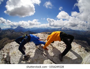 Two Female Mountain Climbers Doing Crazy Yoga Pose On A ,mountain Summit In The Italian Dolomites