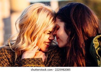 Two Female Putting Heads Together During Sunset.