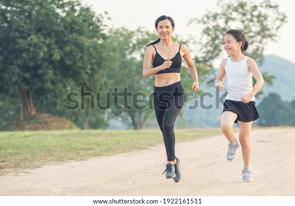 two\
female runners jogging outdoors in forest in autumn\
nature.\
running sporty mother and daughter. woman and child\
jogging in a park. outdoor sports and fitness\
family.