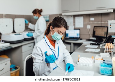 Zwei Wissenschaftlerinnen oder Techniker mit Gesichtsschutzmasken arbeiten im Labor an menschlichen Blutproben.