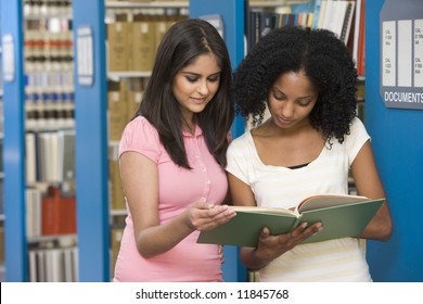 Two Female Students Working Together In Library