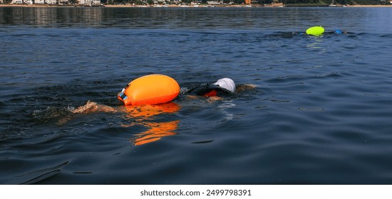 Two female Swimmers are swimming in the Long Island Sound wearing colorful flotation devices for safety. - Powered by Shutterstock