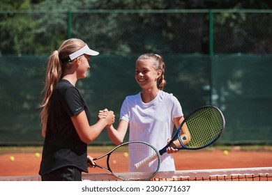 Two female tennis players shaking hands with smiles on a sunny day, exuding sportsmanship and friendship after a competitive match. - Powered by Shutterstock