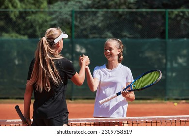 Two female tennis players shaking hands with smiles on a sunny day, exuding sportsmanship and friendship after a competitive match. - Powered by Shutterstock