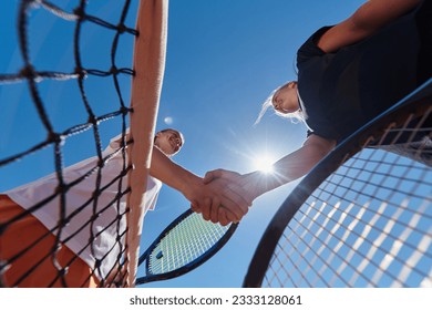 Two female tennis players shaking hands with smiles on a sunny day, exuding sportsmanship and friendship after a competitive match. - Powered by Shutterstock