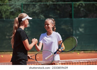 Two female tennis players shaking hands with smiles on a sunny day, exuding sportsmanship and friendship after a competitive match. - Powered by Shutterstock