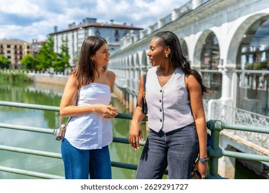 Dos turistas disfrutando de un día de verano en bayonne, Francia, charlando en un puente sobre el río nive