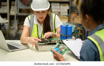 Two Female Warehouse Worker Counting Items In An Industrial Warehouse On The Factory's Mezzanine Floor. Which Is A Storage For Small And Light Electronic Parts.