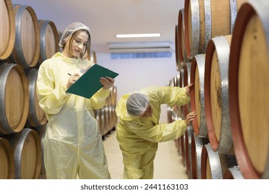 Two female winemaker inspecting quality of storage tank the process of fermentation during manufacturing in winery factory. Concept manufacturing and fermentation winery industry at factory - Powered by Shutterstock