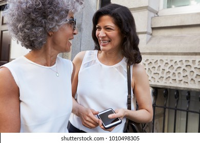 Two Female Work Colleagues Talking In The Street, Close Up