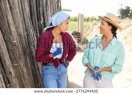 Two female workers having a break. They're standing outdoor and talking about something.