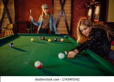 Two females enjoying billiard game on weekend night
