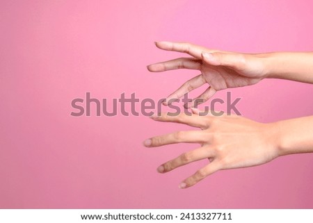 Two female's hands trying to grab or reach something isolated over pink background