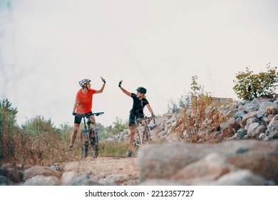 Two Females High Five On Mountain Bike Ride. Happy Senior Women Cyclist Celebrating Success On Riding In Wilderness. Copy Space