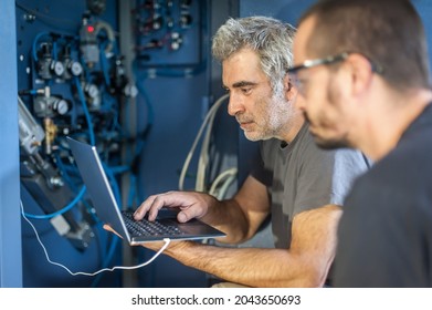 Two Field Service Maintenance Engineer Technician Electrician Inspect And Control Machine Hardware And Software System With Laptop Computer. Electric Installation