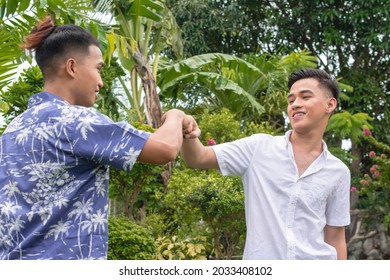 Two Filipino mean fist bumps showing respect or support. Collaborating on a project or greeting each other. Gen Z generation.