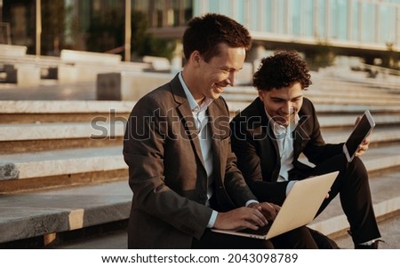 Two financiers have met and are using a laptop. Working on a new project of a colleague.