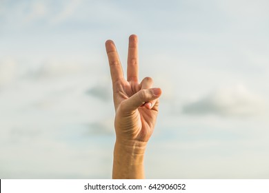 two fingers with sky background hand sign language