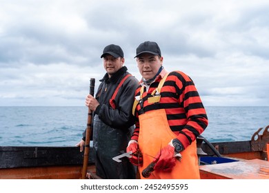 Two fishermen looking at camera while working on a lobster fishing boat - Powered by Shutterstock