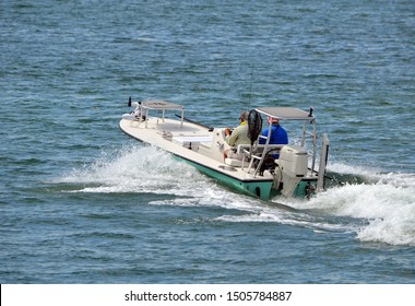 Two Fishermen In A Small Open Fishing Skiff Powered By A Single Outboard Engine