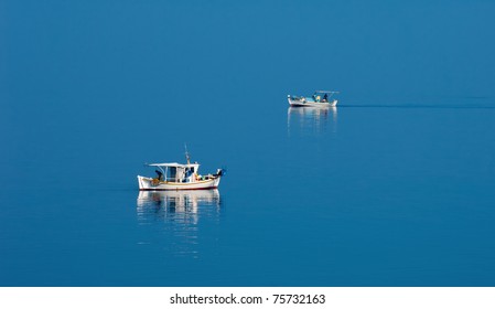 Two fishing boats traveling in opposite directions on calm Greek waters during a peaceful morning