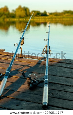 two fishing rods on an old fisherman's bridge on the river, a man's rest, a beautiful landscape, a blurred background. High quality photo