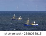 Two fishing vessels in front of an offshore wind park in the North sea near to Egmond aan Zee on a sunny day