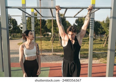 Two fit young adults initializing in pull-ups on monkey bars at a sunny outdoor gym - Powered by Shutterstock