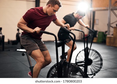 Deux jeunes en vêtements de sport s'entrainant sur des vélos d'exercice à la salle de sport
