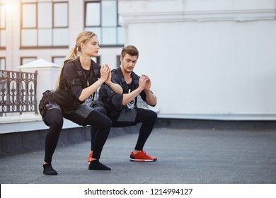 two fit young people bending knees to full squat position. side view full length photo. copy space.