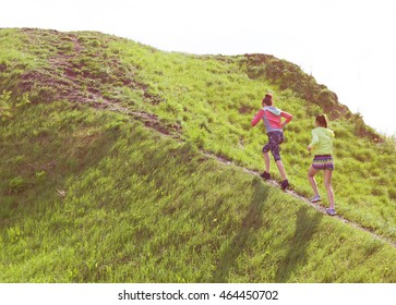 Two fit young women friends exercising in a park running up the hill. Active healthy lifestyle and outdoor workout concept