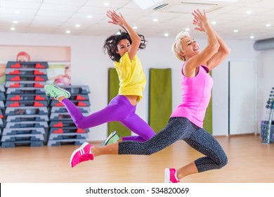 Two fitness models exercising in gym, dancing Zumba.