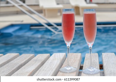 Two flute glasses with pink champagne at swimming pool.
Cruise vacation and celebration concept.