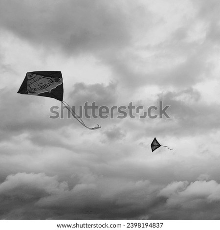 Two flying children kite, paper dragon and sky with clouds, black and white photo