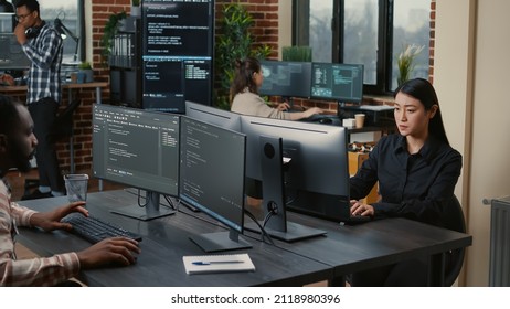 Two focused coders facing each other writing code in software development office while team of coders are developing artificial intelligence. Team of programmers innovating algorithm code. - Shutterstock ID 2118980396